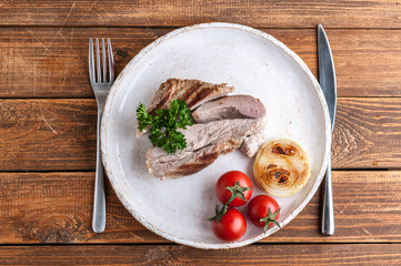 Grilled turkey fillet with spices, herbs and cherry tomatoes on a plate on a wooden table. Top view
