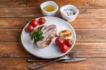 Grilled turkey fillet with spices, herbs and cherry tomatoes on a plate on a wooden table