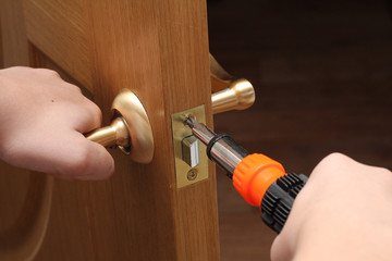 man with a screwdriver in his hand repairs the inner door. door lock