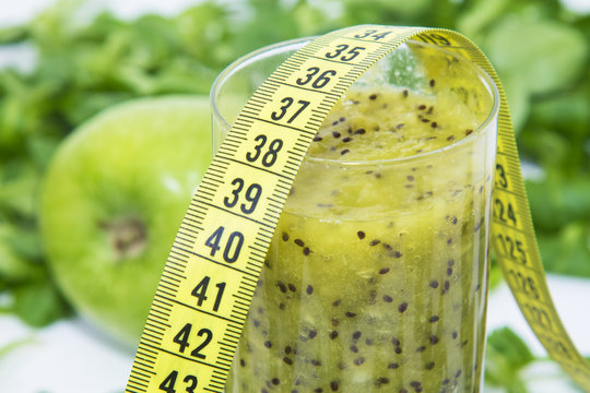 Green smoothie of fruits and vegetables with tape measure. diet and slimming concept