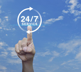 Hand pressing button 24 hours service icon over blue sky with white clouds, Full time service concept