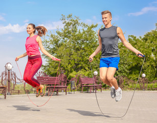Young man and woman with jumping ropes in park