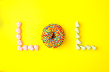 Word lol from sweetness on yellow background. Abbreviation stands for laugh out loud, flat lay trendy background