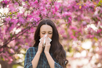 Woman blowing nose because of spring pollen allergy - obrazy, fototapety, plakaty