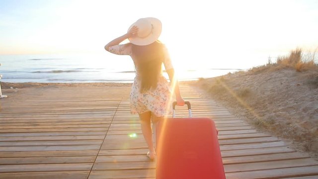 Young stylish woman running with red suitcase. Vacation concept