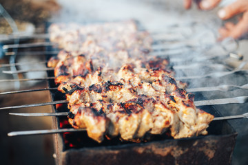 Marinated shashlik preparing on a barbecue grill over charcoal. Shashlik or Shish kebab popular in...