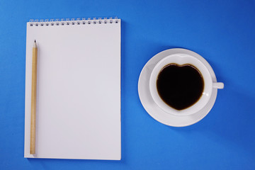 Notepad and coffee on colored background top view