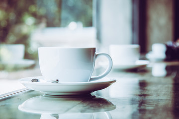 White Coffee Cup placing on table near window with bokeh from outside