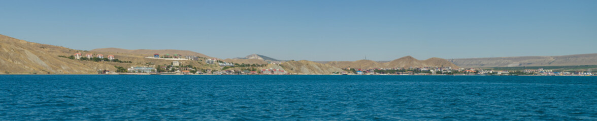 Panorama of the sea coast against a blue sky. Shooting taken from the water side