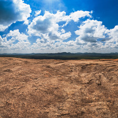 Massive stone and view on blue cloudy sky and green forest