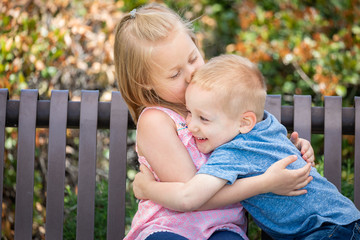Fototapeta premium Young Sister and Brother Having Fun On The Bench At The Park