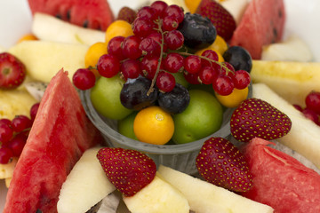 Fruits on a plate. Green plum, red currant, blueberry, strawberry, physalis, pitahaya, watermelon, orange and apple.