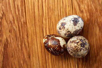 Fototapeta premium Group of three quail eggs on a wooden table, top view, close-up, selective focus, copy space.