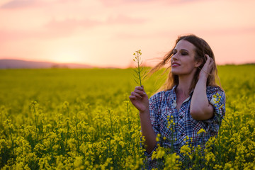 Naklejka na ściany i meble Happy young woman in a field of canola seed in bloom. Freedom, nature, ecology and happiness concept.
