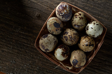 Quail eggs in a box on a vintage wooden background, top view, selective focus.