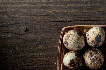 Quail eggs in a box on a vintage wooden background, top view, selective focus.