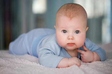 Portrait of a baby boy who lies on his stomach in a blue suit