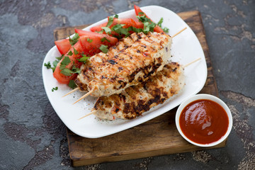 White tray with chicken lula kebabs and fresh vegetables on a brown stone background, horizontal shot