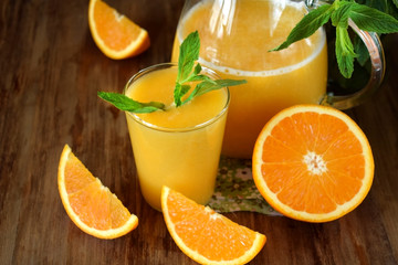 Orange juice in a glass and jug on a wooden table