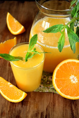 Fototapeta na wymiar Orange juice in a glass and jug on a wooden table