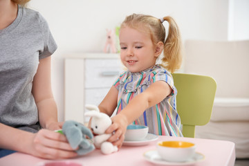 Mother and cute little girl playing at home