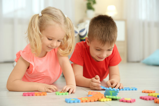 Cute little children playing with pazzles at home