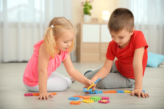 Cute little children playing with pazzles at home