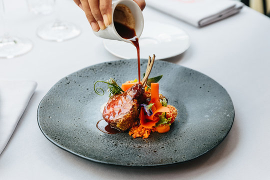 Modern French cuisine: Roasted Lamb neck & rack served with carrot, yellow curry pouring lamb sauce. Served in black stone plate