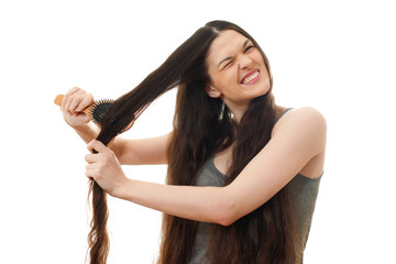 A young woman can not comb out the problematic tangled hair. White background close up