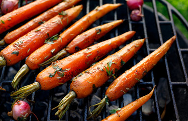 Gegrillte Karotten in einer Kräutermarinade auf einer Grillplatte, im Freien, Draufsicht. Gegrilltes vegetarisches Essen, Grill