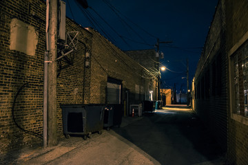 Dark and eerie urban city alley with vintage warehouses and factory buildings at night