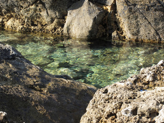 Naklejka na ściany i meble Crystal clear sea water between rocks . Tuscany, Italy