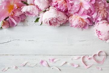 Pink peonies and hearts on a wooden background for congratulations, invitations