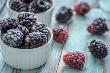Frozen Dewberries in hoarfrost on rustic wooden table. Close up
