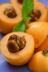 Fresh ripe Loquat Nispero cuted with mint leafs on purple background Close up.