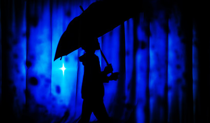 Girl with umbrella in rain drops falling on blue background. Concept for bad weather, winter or protection