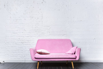 Pink retro sofa against white brick wall