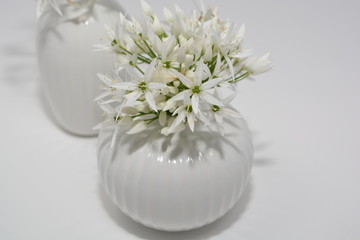 zwei kleine, weiße Blumenvasen mit Bärlauch