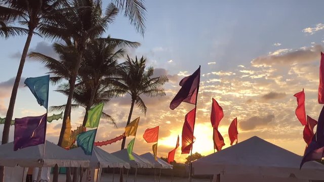 Sunrise behind colorful flags with palm trees