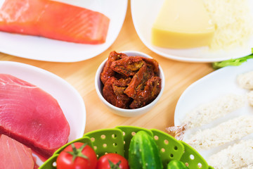 Raw appetizing fillet of tuna on a table with a yard of Greek salad with salmon and lemon cucumbers and tomatoes as well as cheese. The concept of a delicious and healthy home-made meal