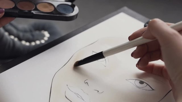 A young woman make-up artist learns to apply make-up using the face map. The makeup artist comes up with makeup using a face chart. The artist on makeup and beauty creates a beautiful face makeup