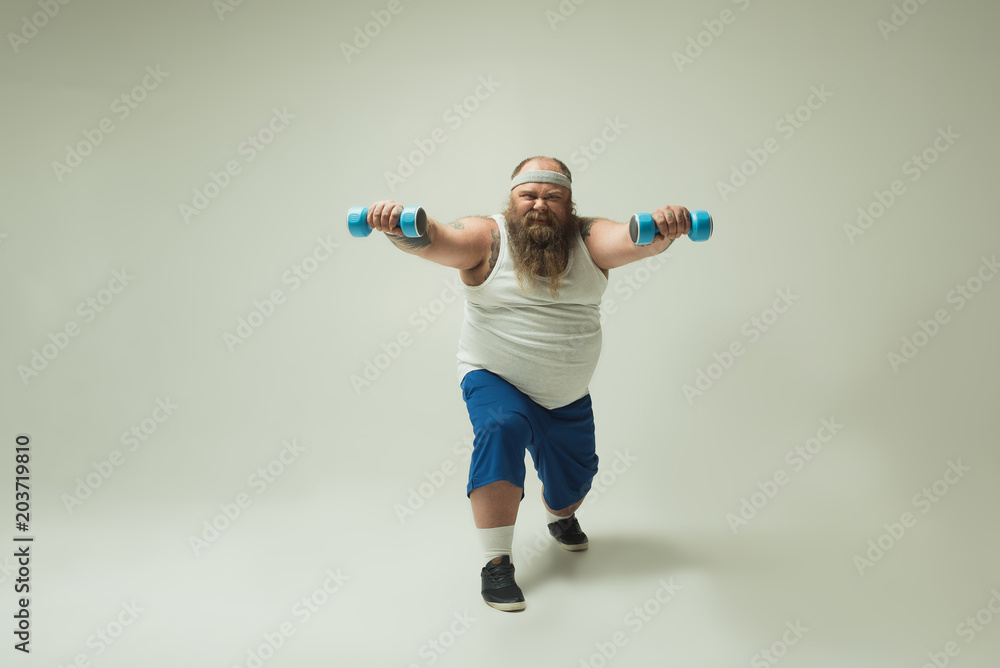 Wall mural man with beard exercising with dumbbells