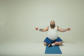 Man meditating on a yoga mat - obrazy, fototapety, plakaty