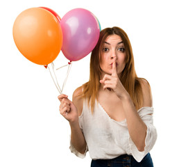 Beautiful young girl holding a balloon and making silence gesture