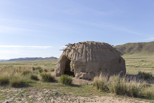 An old clay yurt in the spring steppe under a clear blue sky. Eastern Kazakhstan