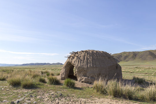 An old clay yurt in the spring steppe under a clear blue sky. Eastern Kazakhstan