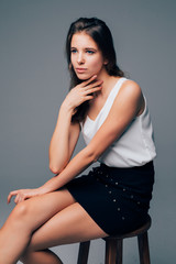 Naklejka premium Beautiful woman sitting on chair, isolated on gray background