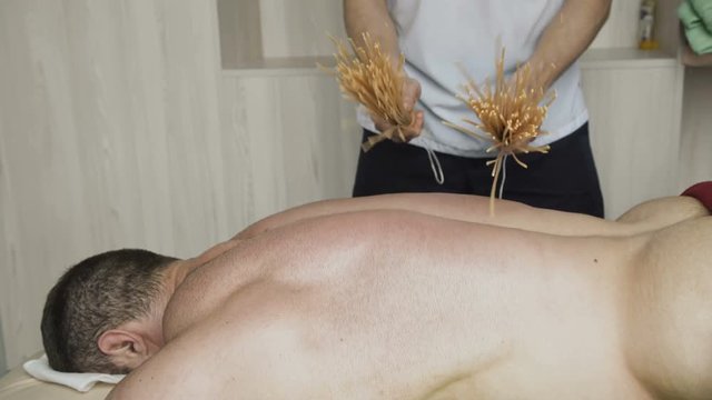 The massage therapy, beating with bamboo stricks male back. 4K