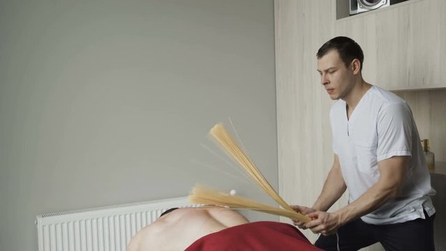 The massage therapy, beating with bamboo stricks male back. 4K