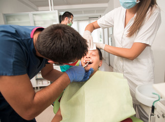 Obraz premium Boy with perfect teeth at the dentist doing check up with the clinic at the background - oral hygiene health care concept